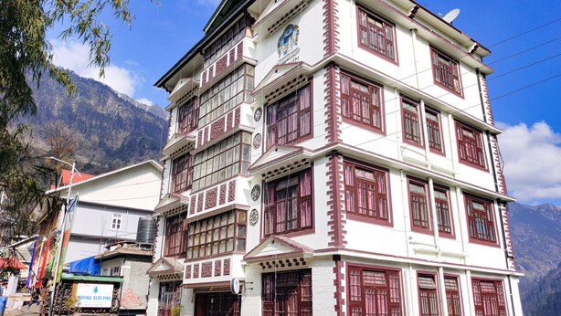 A multi-story building with traditional architecture, featuring multiple balconies and large windows. - Rufina Blue Pine (Chungthang)