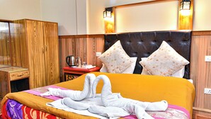 A hotel room with a bed, a wardrobe, a bedside table with a kettle, and two wall-mounted lamps. - Rufina Blue Pine (Chungthang)