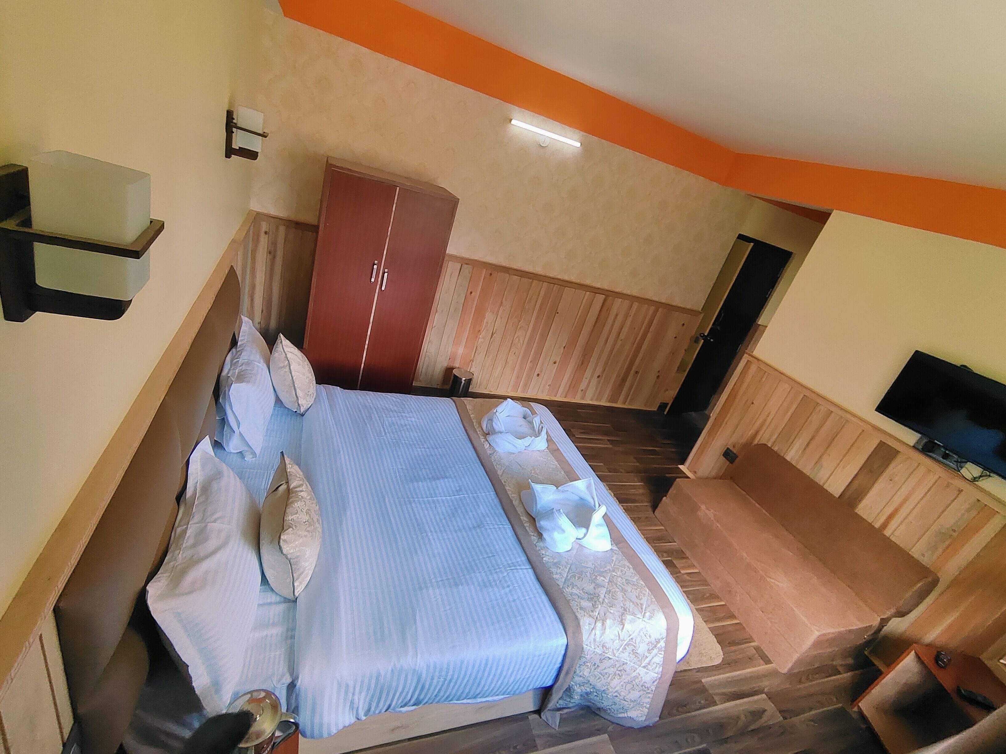 Una habitación de hotel con cama, armario, televisión y una pequeña zona de estar.