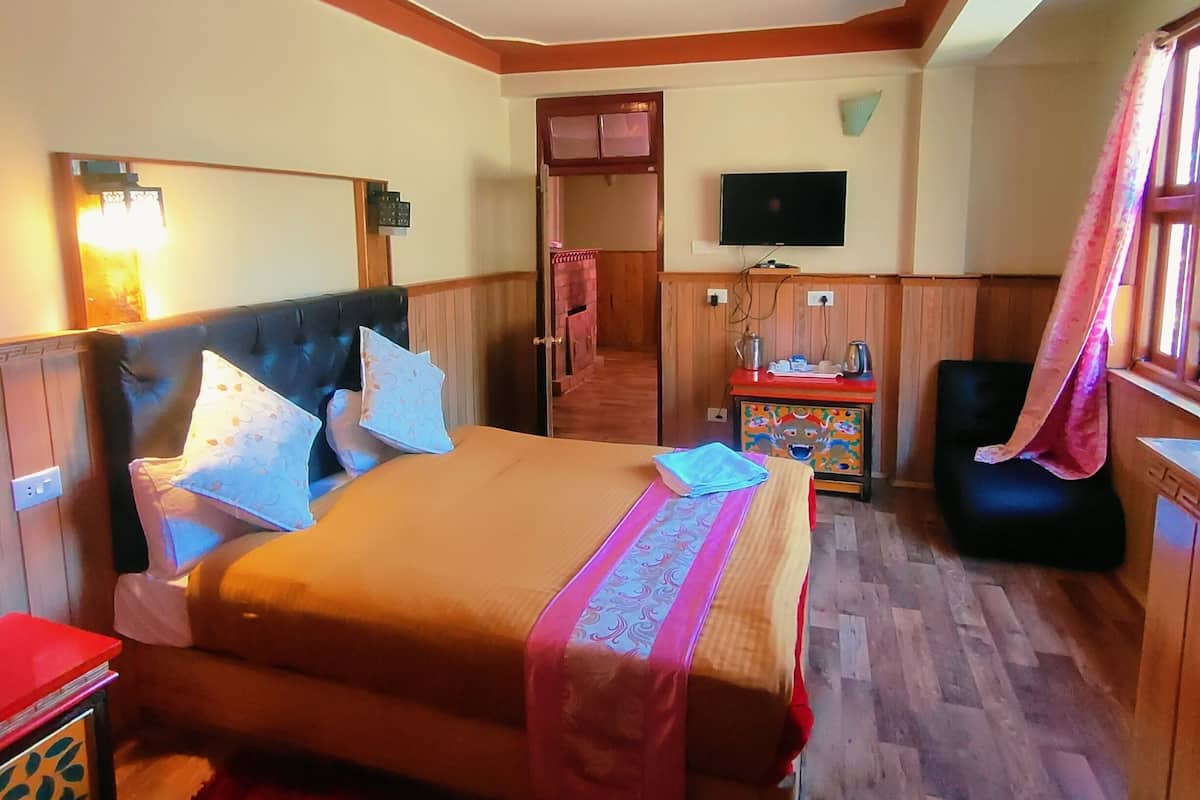 A hotel room with a bed, a TV, a desk, and a chair.