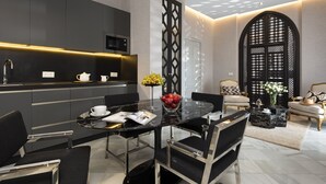 Una cocina moderna con encimera negra, microondas y pileta. Hay un comedor con mesa de vidrio y sillas, además de un florero decorativo con flores.