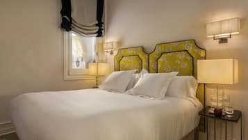 A neatly made bed with white linens, a headboard with a floral pattern, and bedside lamps on either side.