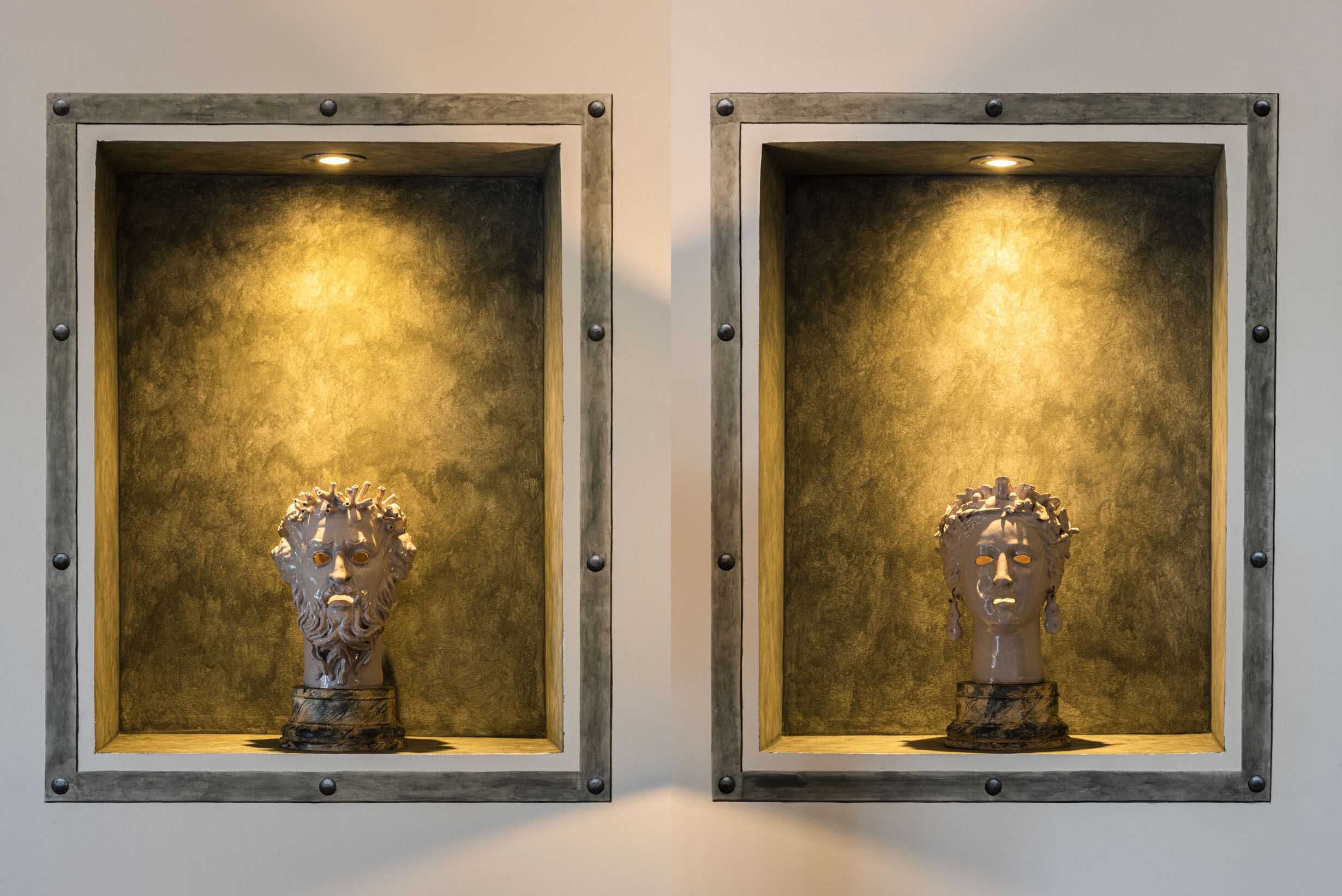 Two identical bust sculptures in framed display cases with a textured background.