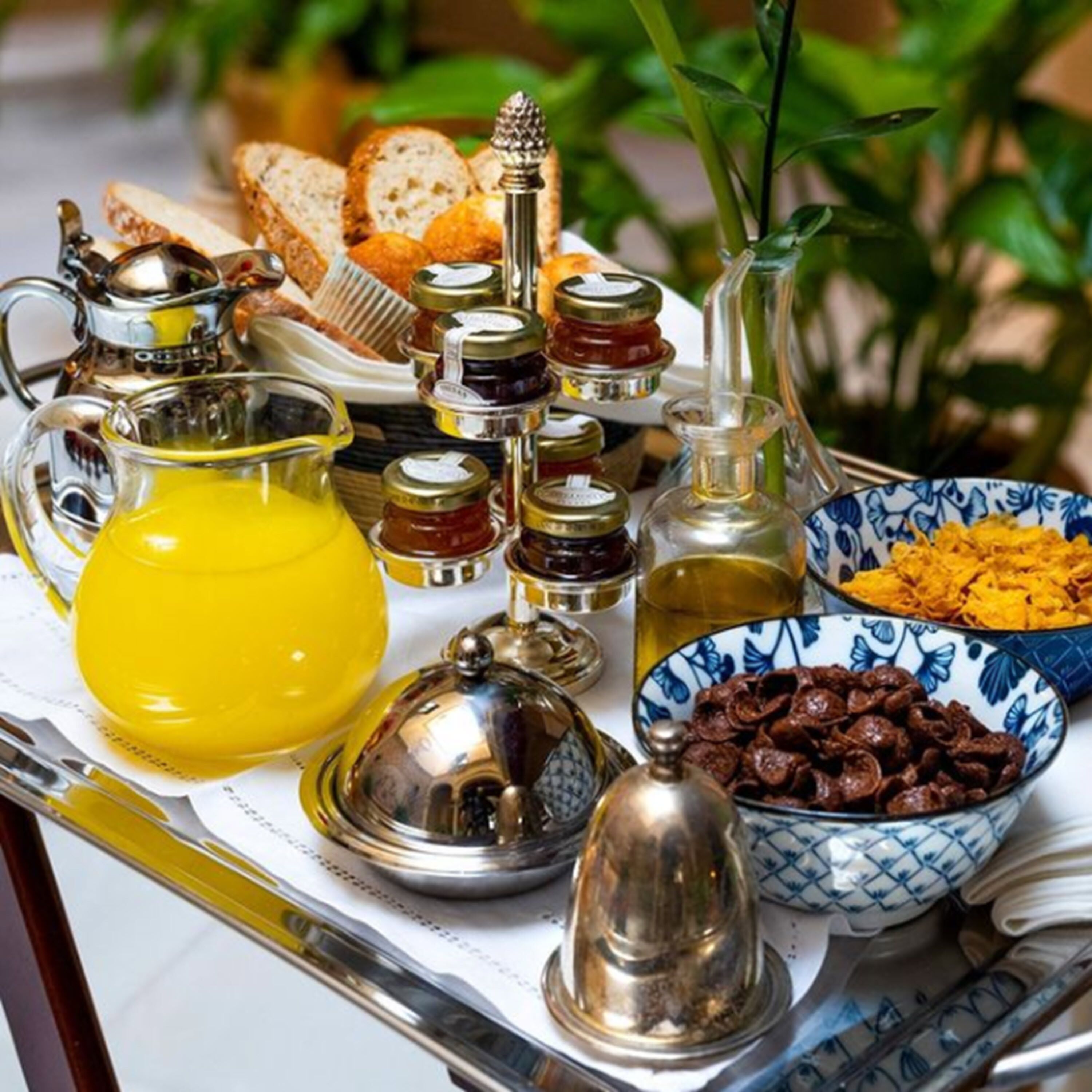 A breakfast tray with various food items and condiments, including bread, olives, and jars of preserves.