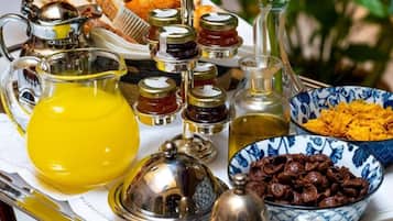 A breakfast tray with various food items and condiments, including bread, olives, and jars of preserves.