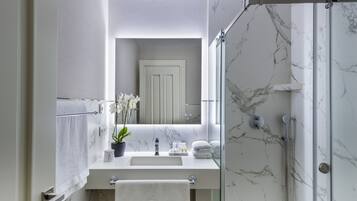 Ein modernes Badezimmer mit Marmorwaschbecken, einer Duschkabine aus Glas und einer Topfpflanze mit Orchideen.