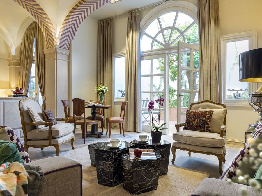 A spacious living room with high ceilings, large windows, and elegant furniture.