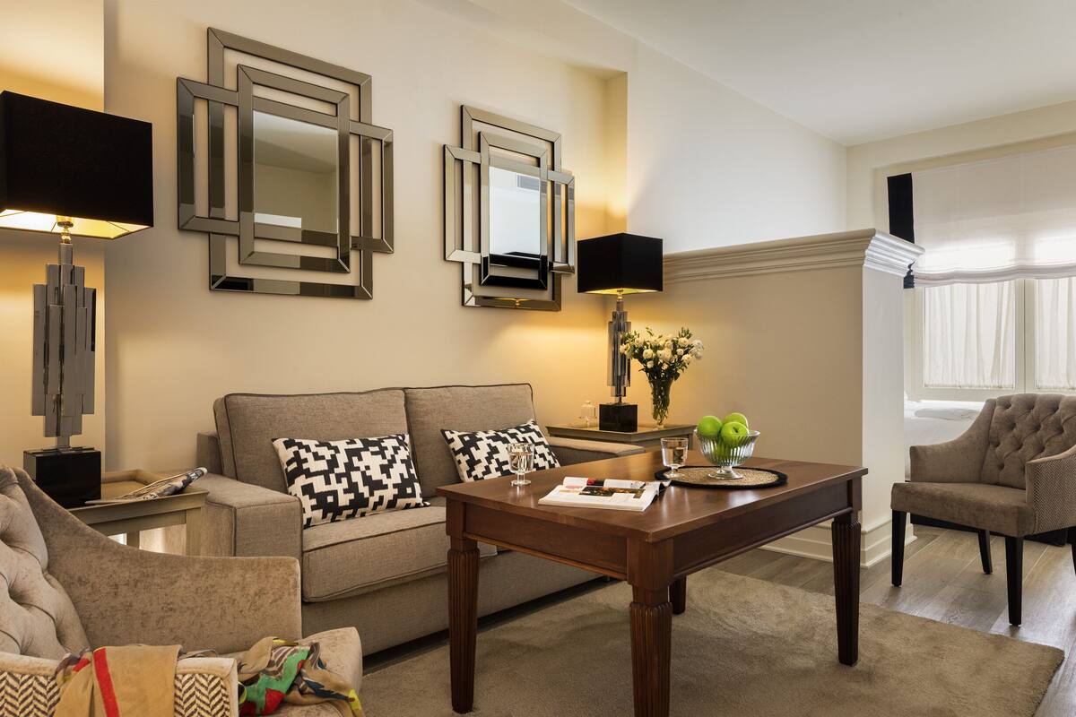 Een woonkamer met een bank, fauteuils, een salontafel en decoratieve spiegels.