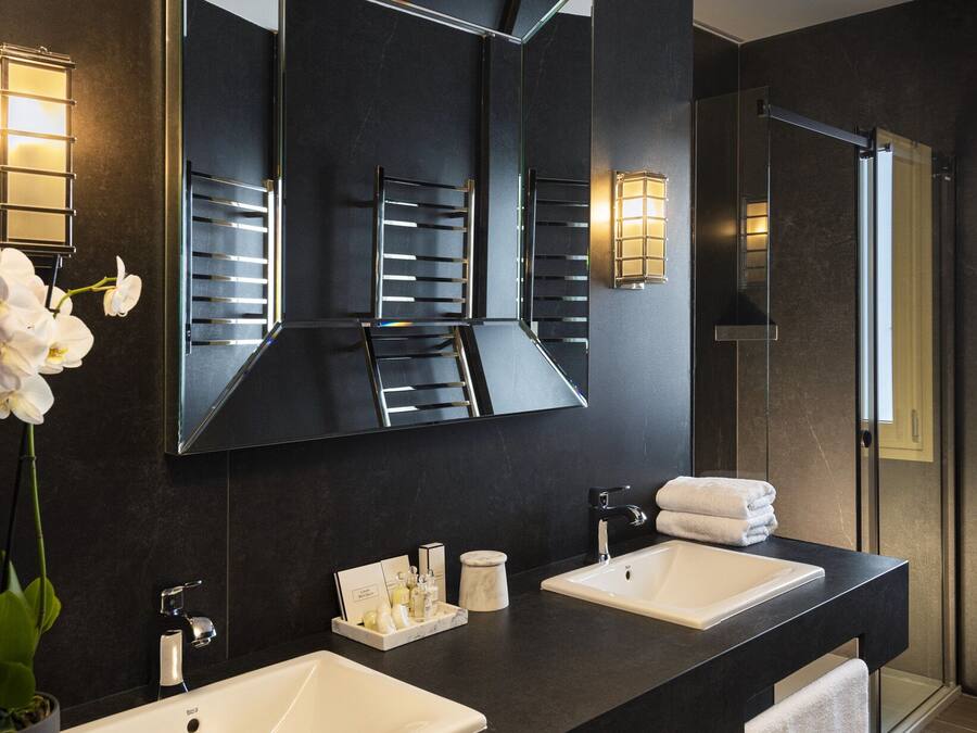 Un baño moderno con dos lavamanos, un espejo grande y una orquídea en maceta.