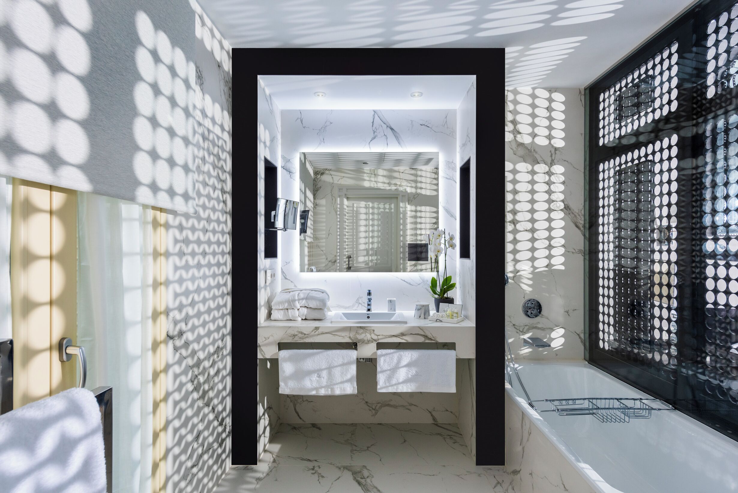 Ein modernes Badezimmer mit einem мраморной раковиной, zwei Handtüchern, einem Spiegel und einer Badewanne.