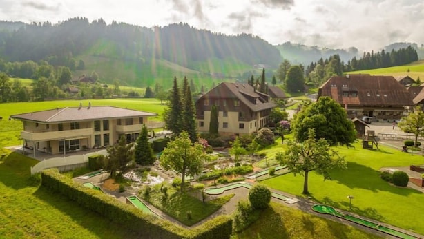 Zona residencial con casas, un campo de golf y montañas al fondo.