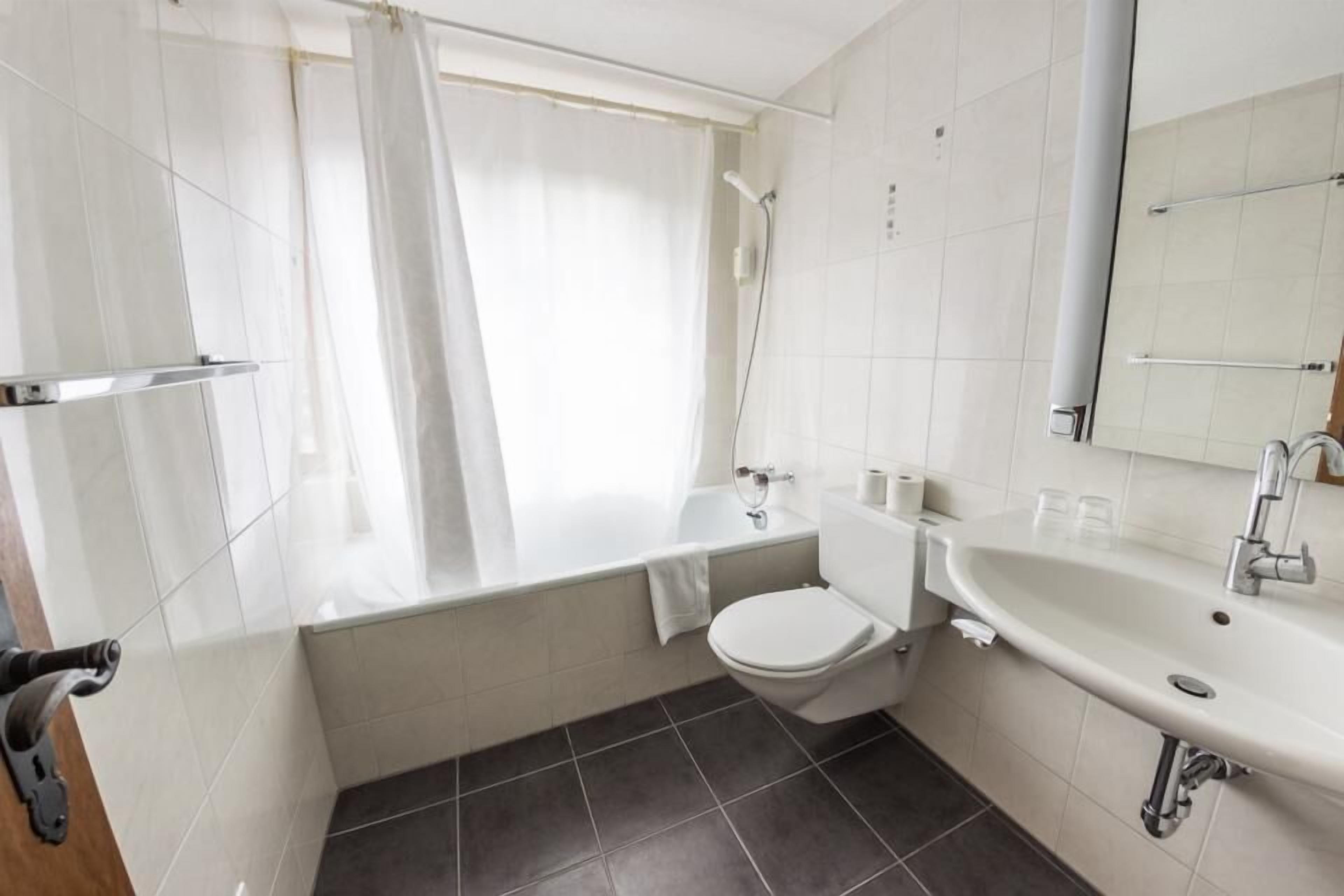 A modern bathroom with a bathtub, toilet, and sink.