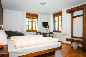 Un dormitorio con cama, escritorio, silla, televisor y ventana.