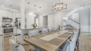 A spacious kitchen with modern appliances, a large dining area with a central island, and a staircase leading to an upper level. - Gulf Views with Pool and Sun Deck Space (Destin)