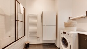 A compact laundry room with a washing machine, a drying rack, and a small trash bin. - L'Estrade 4* - Appartement 2 bedrooms with the view lake & garage (Annecy)