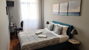 A neatly arranged bedroom with a bed, bedside lamps, a desk, and a chair. - Cool Guesthouse (Porto)