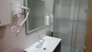A bathroom with a white sink, a mirror, and a hairdryer mounted on the wall. - Cool Guesthouse (Porto)