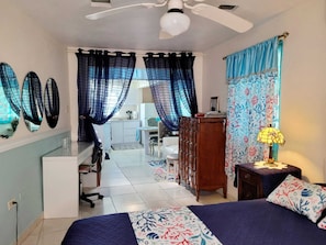 A bedroom with a bed, a desk, a wardrobe, and a ceiling fan.