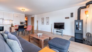 Un salon moderne avec un canapé, une table basse et un téléviseur. Il y a également un coin cuisine équipé de placards et d’un four à micro-ondes.