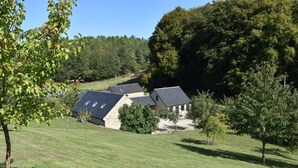 A house with a sloped roof, surrounded by a grassy area and trees. - The Cotswold Manor Wychwood, with Hot-Tub, Games Barn, 3 acres of Parkland (Witney)
