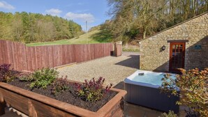 A stone building with a wooden door, a hot tub, and a wooden fence. - The Cotswold Manor Wychwood, with Hot-Tub, Games Barn, 3 acres of Parkland (Witney)