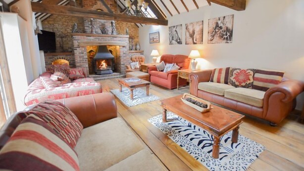 A cozy living room with a fireplace, leather sofas, and wooden flooring. - The Cotswold Manor Wychwood, with Hot-Tub, Games Barn, 3 acres of Parkland (Witney)