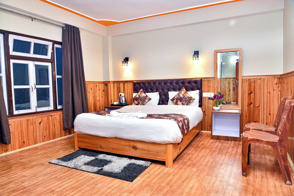 Une chambre à coucher aux murs lambrés, avec un grand lit, une table de chevet, un miroir et une chaise.