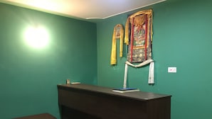 A reception desk with a dark wood finish, a green wall, and a patterned floor. - Rufina Lachen Deezong (Chungthang)