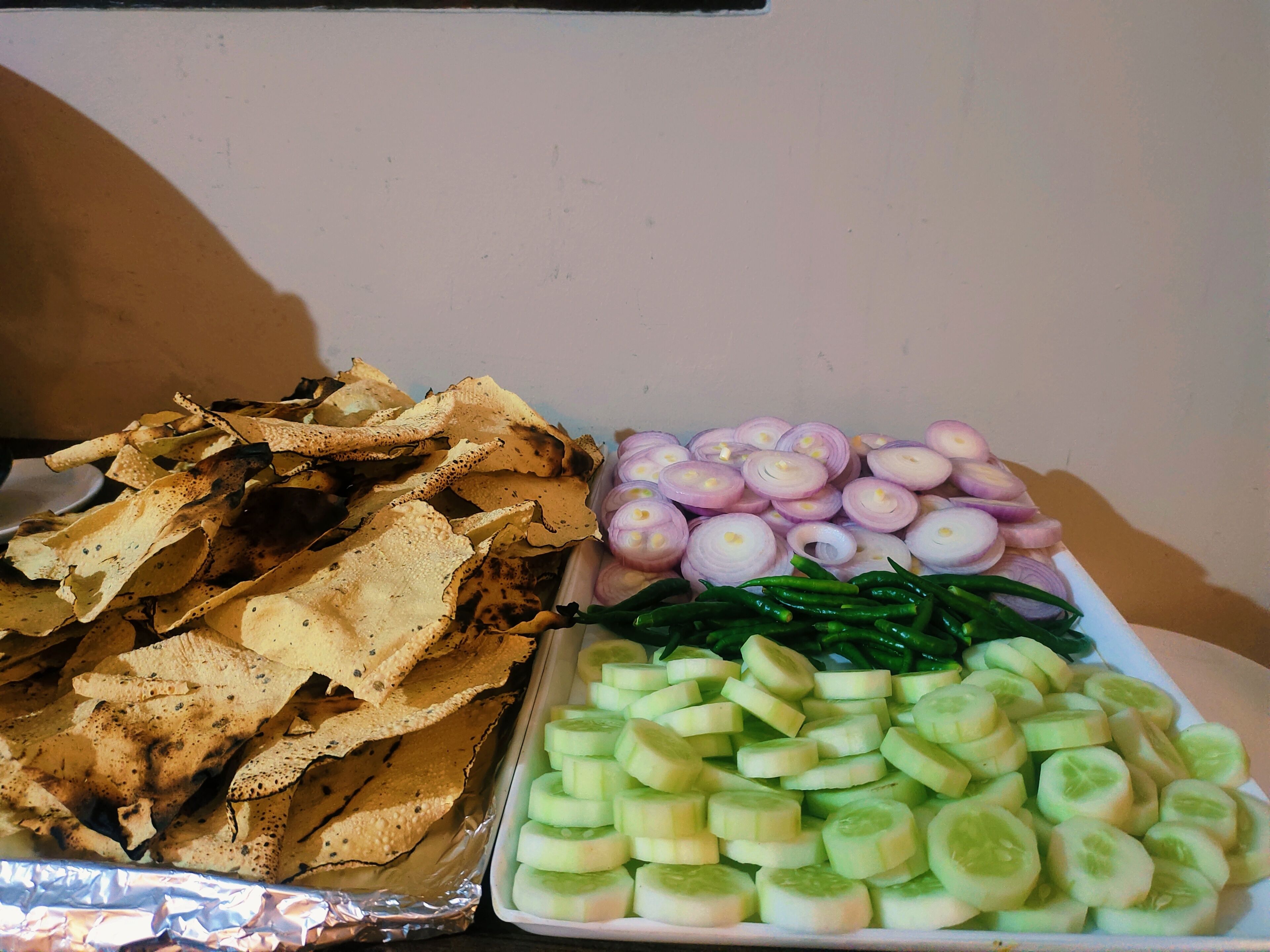A tray with sliced cucumbers, sliced onions, and tortilla chips.