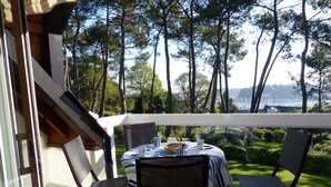 Een balkon met een tafel gedekt voor twee, met uitzicht op een mooi landschap van bomen en water.