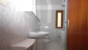Un bagno con lavandino, water e lavatrice.