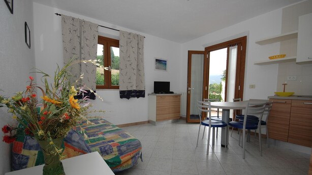 Una stanza con un letto, un tavolo da pranzo con sedie, un angolo cottura e una TV su un mobile.