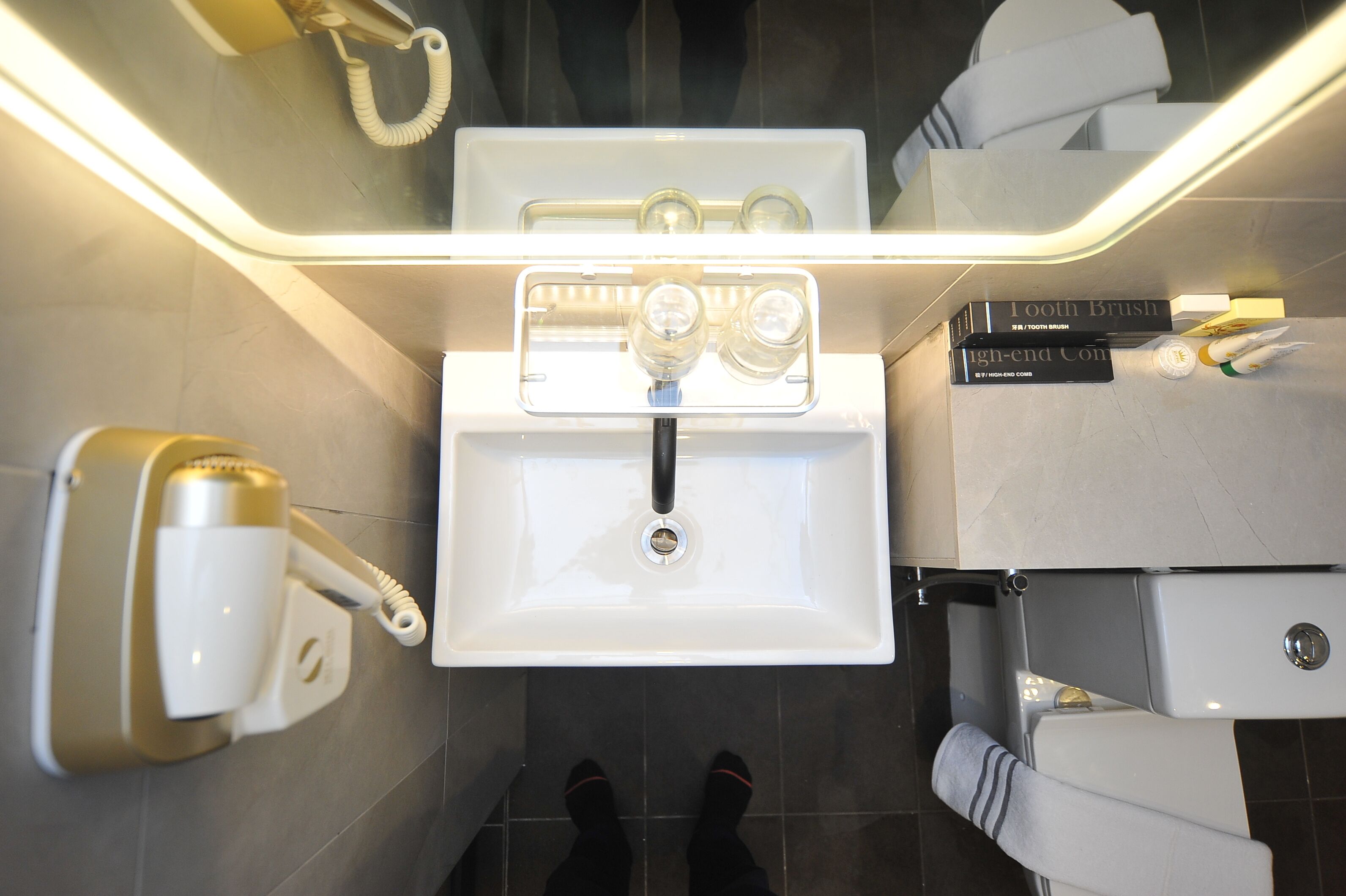 A modern bathroom with a white sink, a hairdryer, and a toilet.