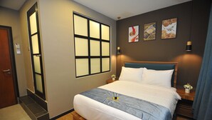 Hotelkamer met een groot bed, een raam met zonwering, een nachtkastje met lamp en kunst aan de muur.