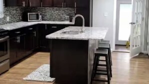 Una cocina moderna con armarios oscuros, encimera de granito y microondas integrado.