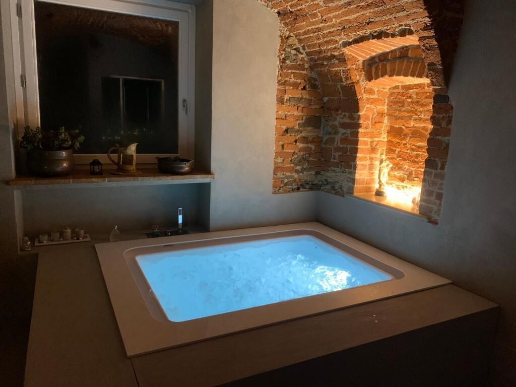 A bathroom with a large bathtub, a window, and a brick wall.