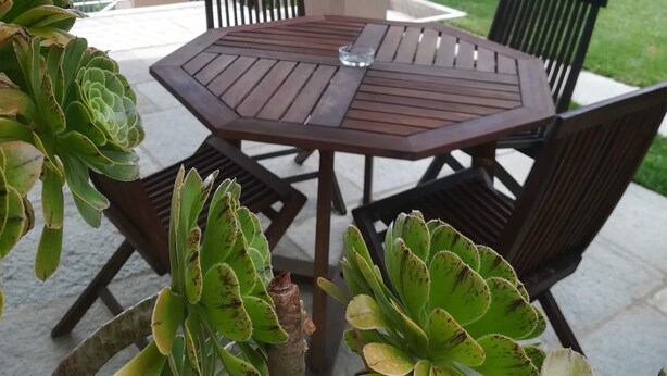 A covered patio area with a round table and chairs, surrounded by potted plants. - B&B Villa Antilia (Busca)