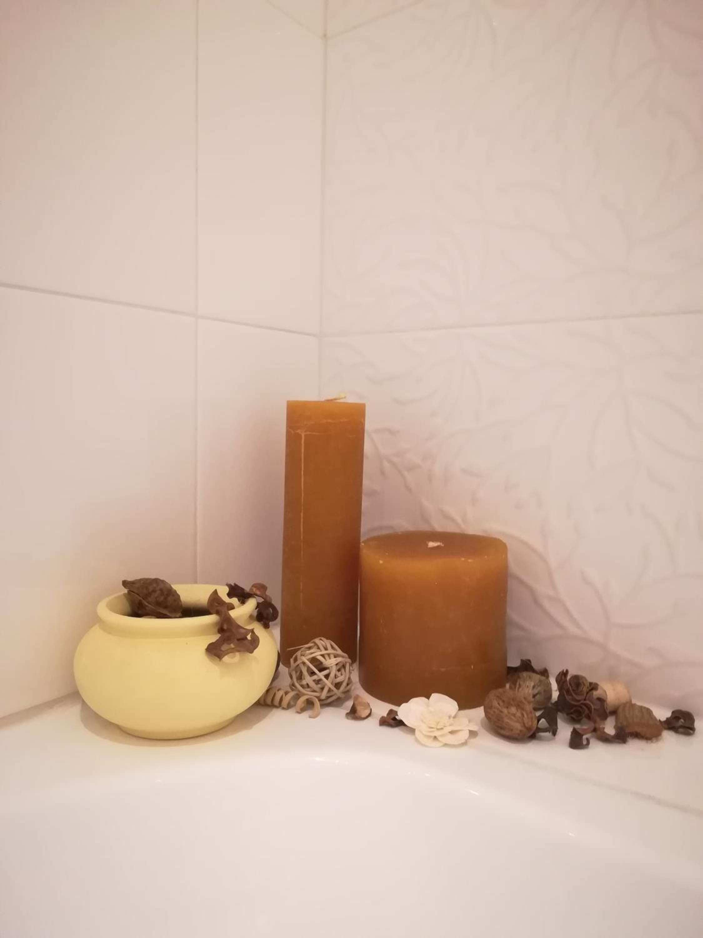 Ein Badezimmer mit einer Badewanne, einem gelben Keramikbecken und zwei Kerzen.
