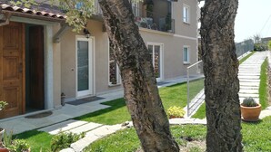 A two-story building with a balcony, a wooden door, and a small garden area with potted plants. - B&B Villa Antilia (Busca)