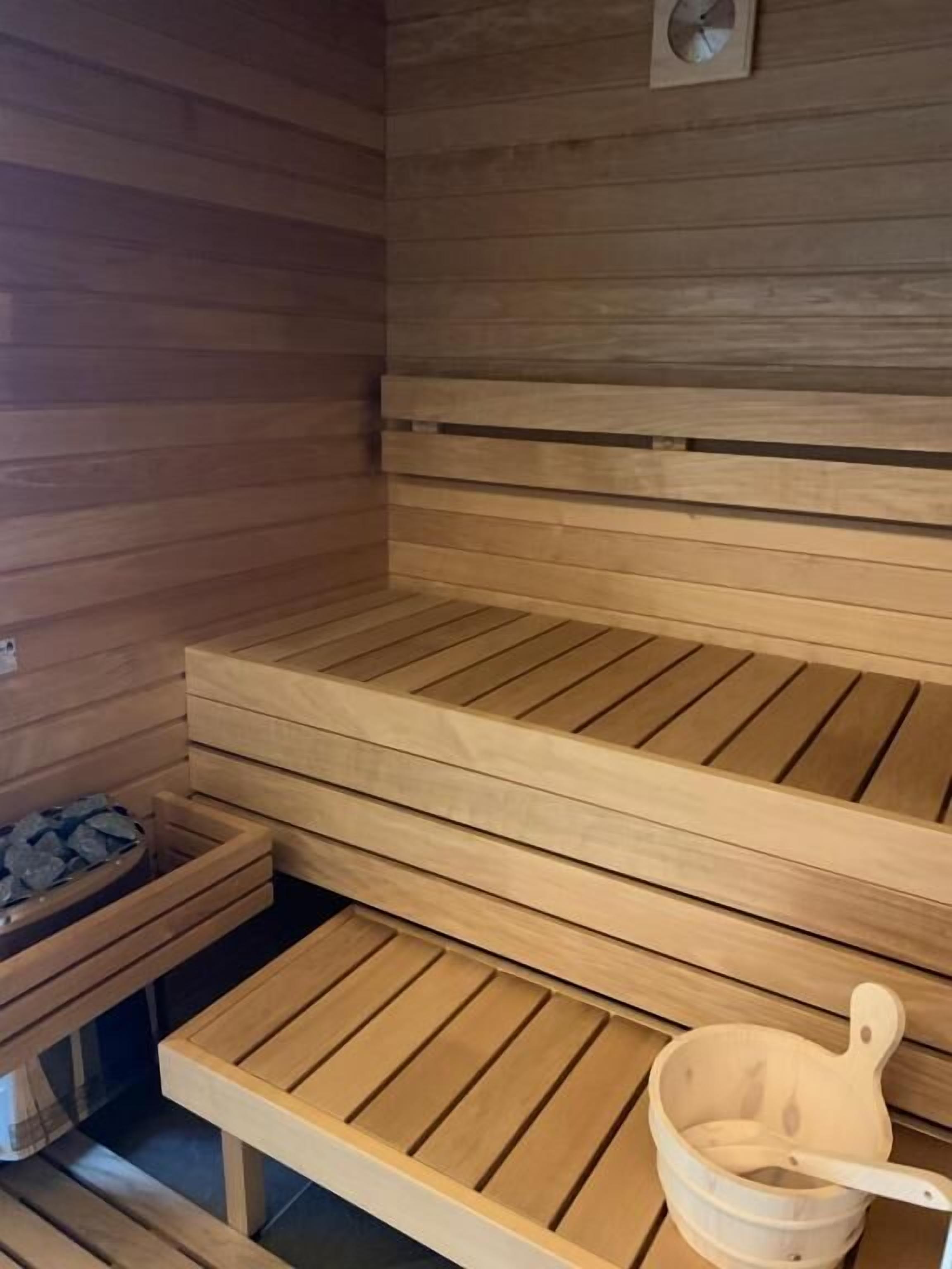 Una sauna con bancos de madera y un cubo de madera.