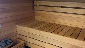Una sauna con bancos de madera y un cubo de madera.
