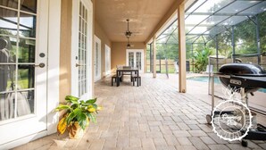 A covered patio with a pool, a grill, and a table with chairs. - Oviedo Charmer - Heated Pool - Close to everything (Oviedo)