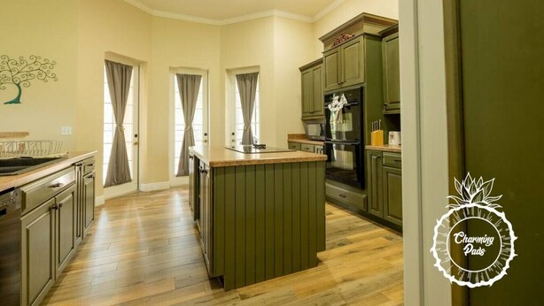 A kitchen with wooden flooring, green cabinets, a central island, and a microwave. - Oviedo Charmer - Heated Pool - Close to everything (Oviedo)