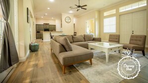 A spacious living room with a sectional sofa, a coffee table, and two armchairs. A kitchen is visible in the background, and there is a ceiling fan. - Oviedo Charmer - Heated Pool - Close to everything (Oviedo)