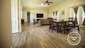 A spacious living room with a wooden floor, a dining area with a table and chairs, a sofa, and a ceiling fan. - Oviedo Charmer - Heated Pool - Close to everything (Oviedo)