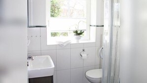 A bathroom with a white sink, toilet, and a window with a plant.