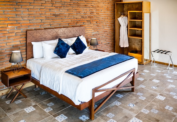 Un lit bien fait, avec un cadre en bois, deux tables de chevet avec des lampes, un plaid bleu et un mur en briques en arrière-plan.