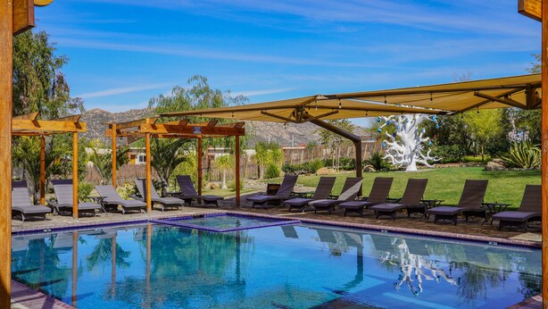 Un área de piscina con sillas de descanso y una pérgola.