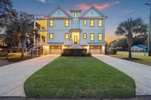 A large, light-colored building with a symmetrical facade, a central entrance with steps, and a well-maintained lawn.