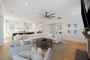 A spacious living room with a large sectional sofa, a coffee table, and a ceiling fan.
